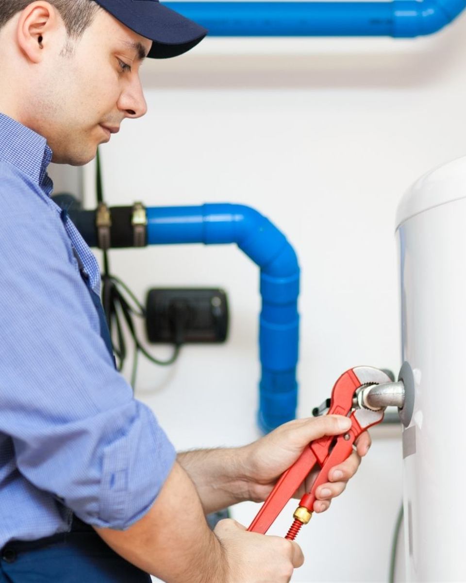 Plumber connecting water lines on a replacement water heater in a Rockingham County crawl space